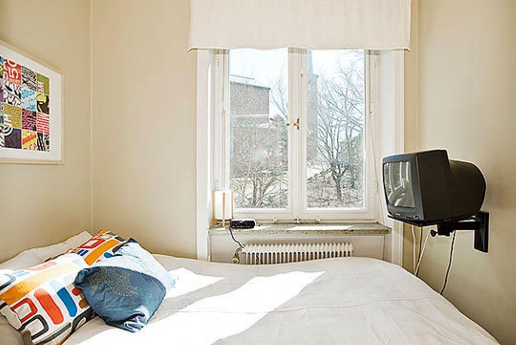 Телевизор в маленькой комнате. Планировка узкой спальни. Кровать возле окна. Телевизор в узкой спальне на стене.